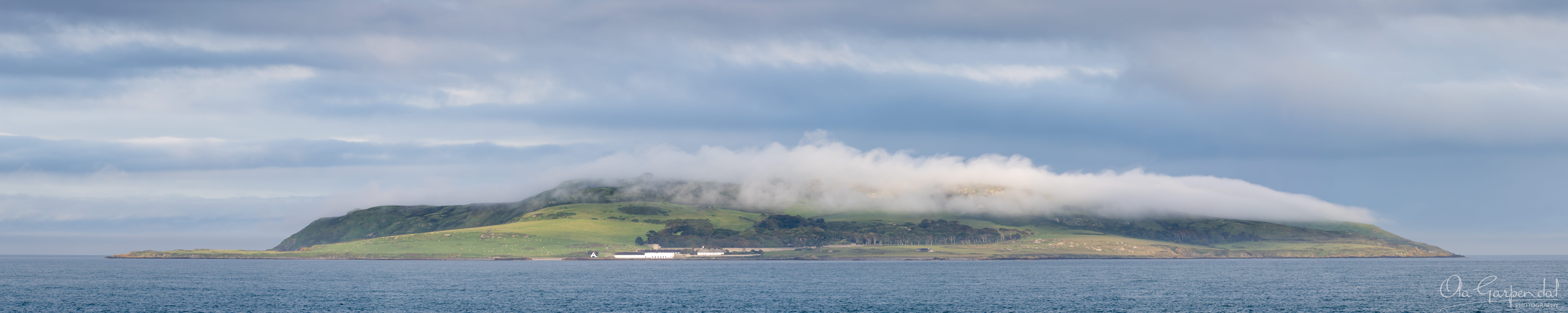 Lambay Island, island with gently sloping green hills partially wrapped in low cloud, photographed by Ola Garpendal Photography