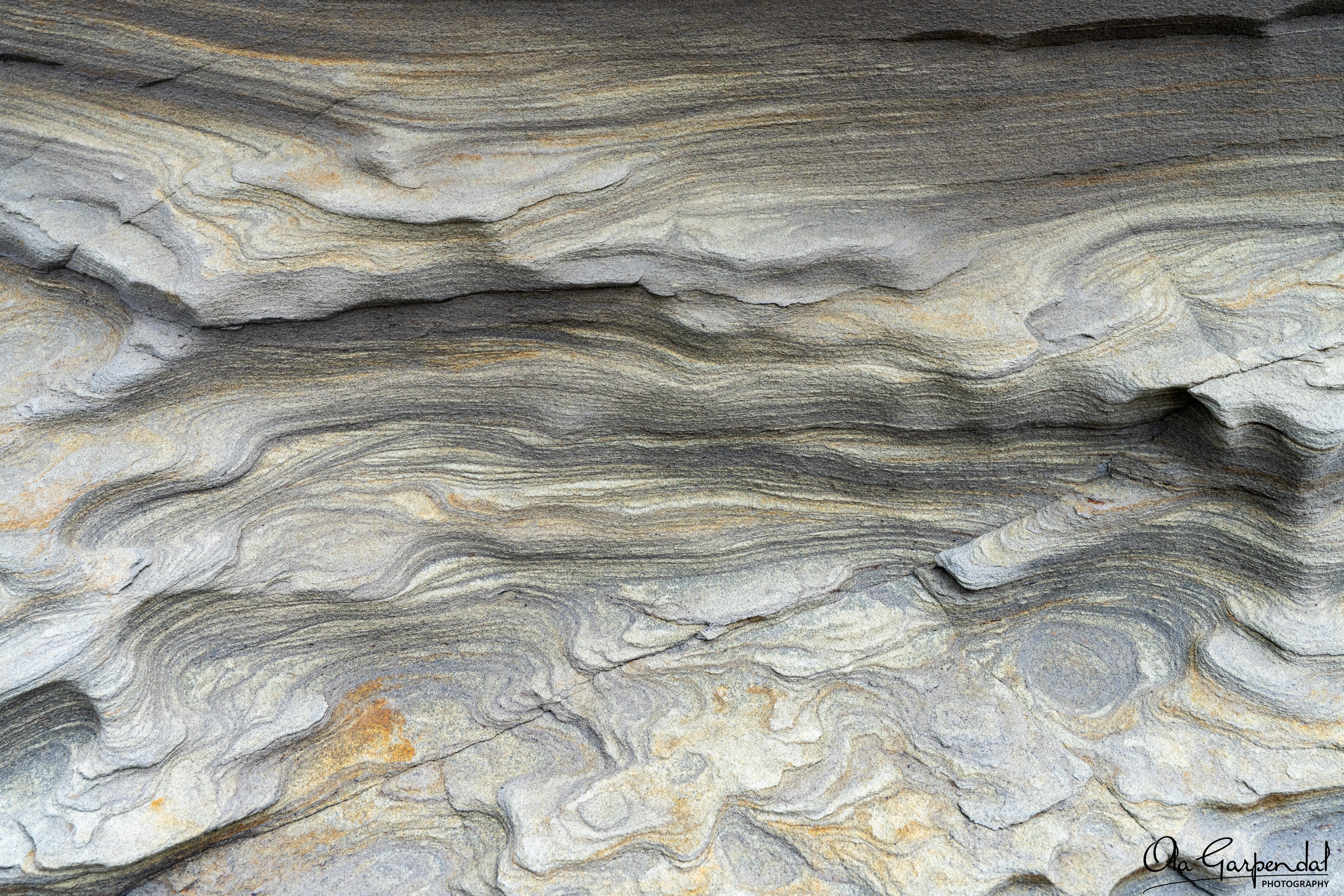 “Rock Ripples” — a detailed abstract view of folded metamorphic rock with flowing grey bands and curved mineral layers, photographed by Ola Garpendal Photography