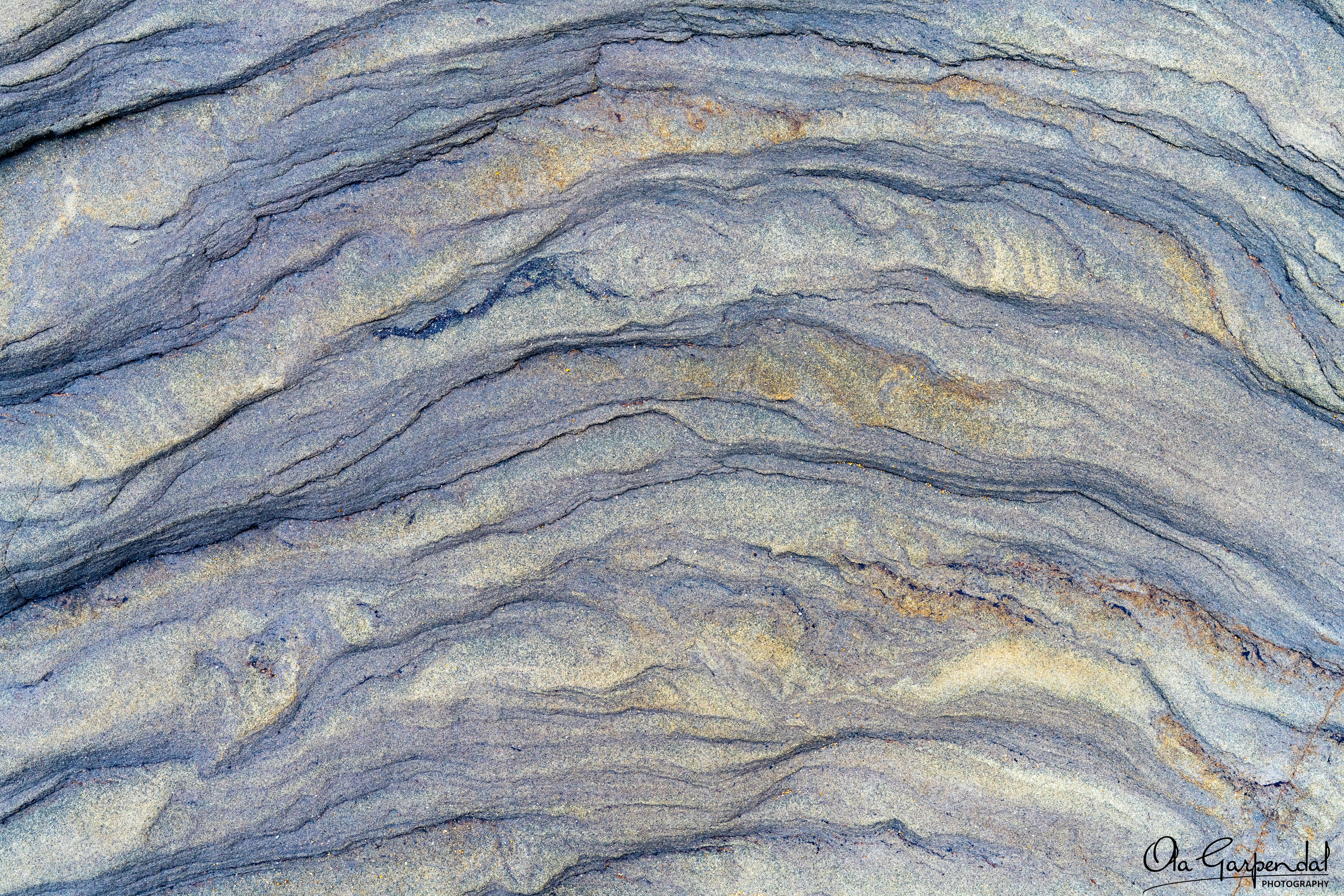 “Rock Wave” — a close‑up abstract view of layered sedimentary rock with soft wave‑like bands and fine textures, photographed by Ola Garpendal Photography
